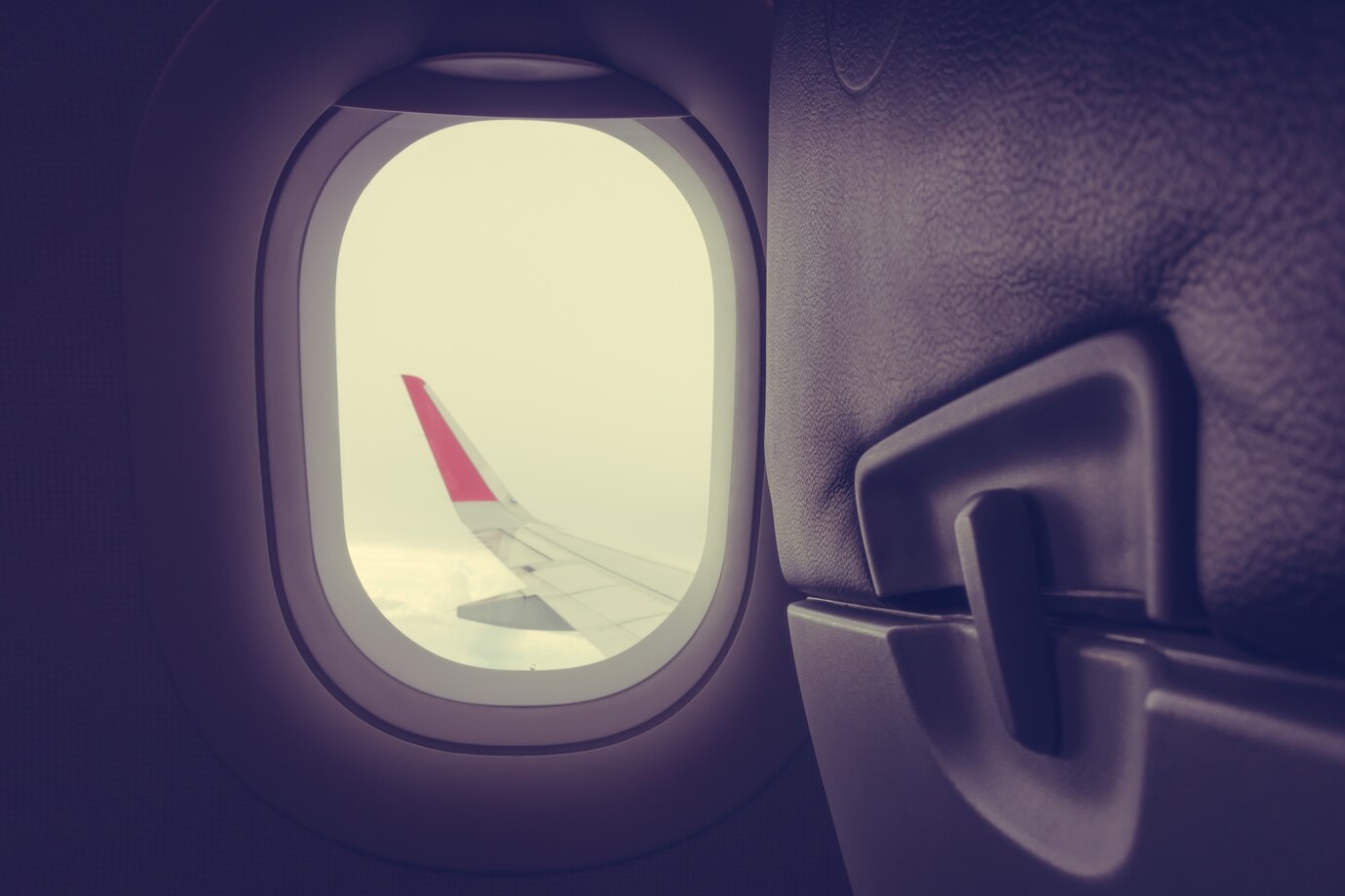 An aircraft wing seen through a cabin window in evening light